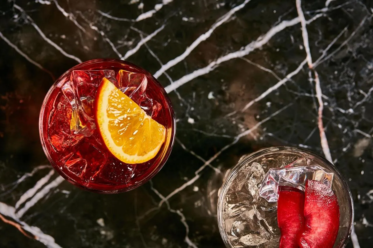 Two cocktails with orange slices served at the bar of The Columbia, Lancaster Gate