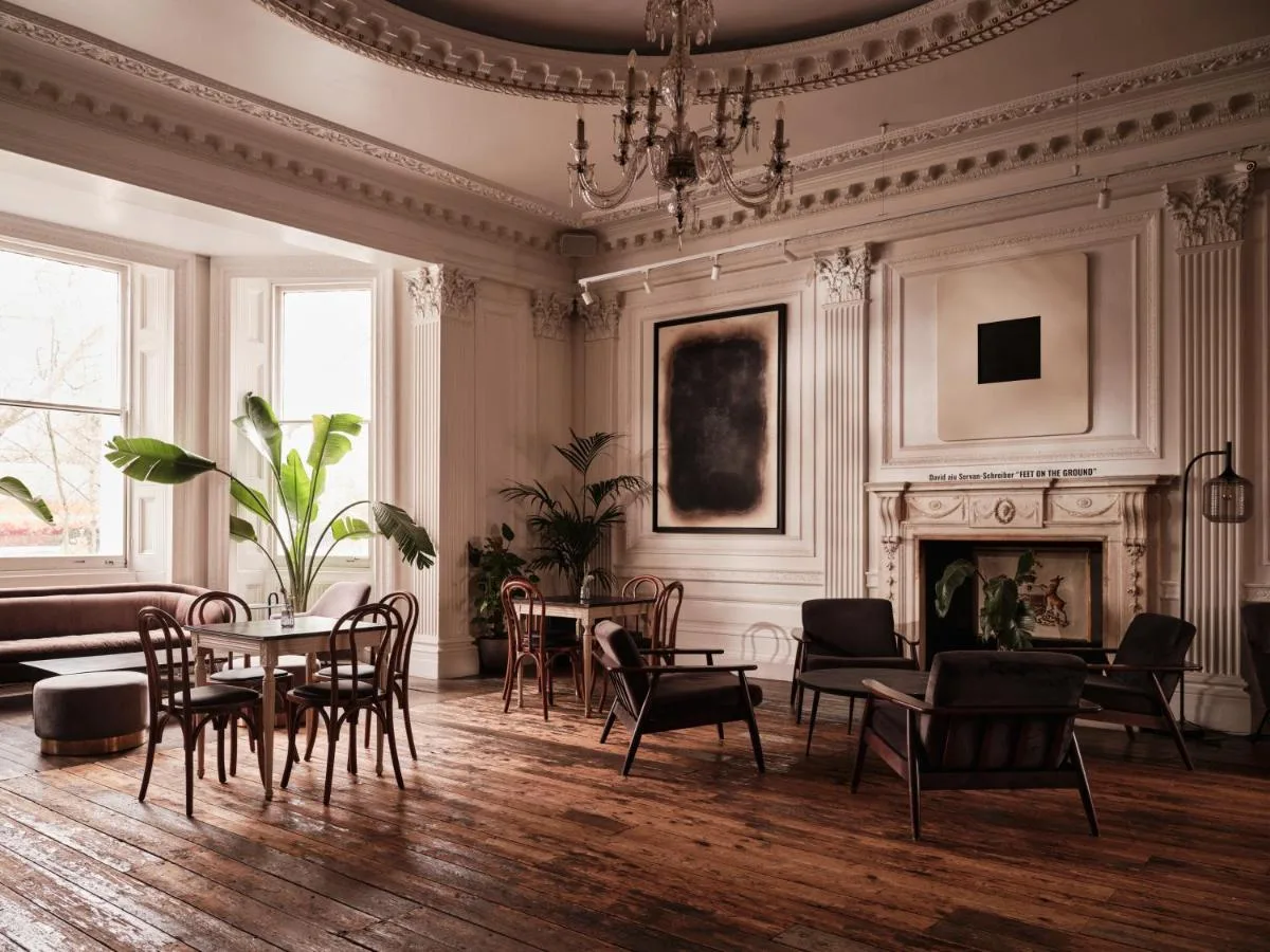 A lounge room with a table, chairs and fireplace at The Columbia, Lancaster Gate